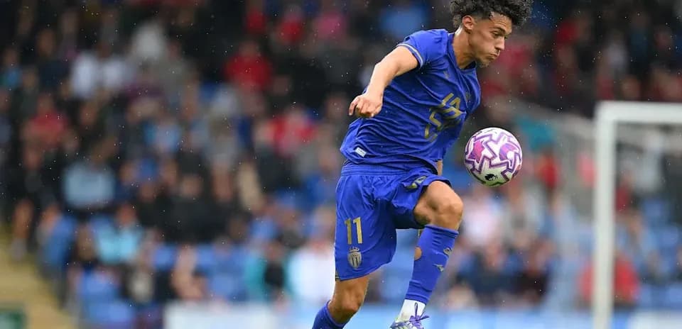 Jugador de fútbol controlando el balón en campo lluvioso