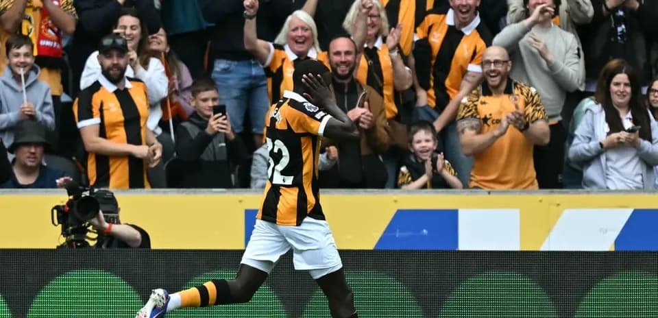 Jugador celebrando un gol frente a aficionados animando