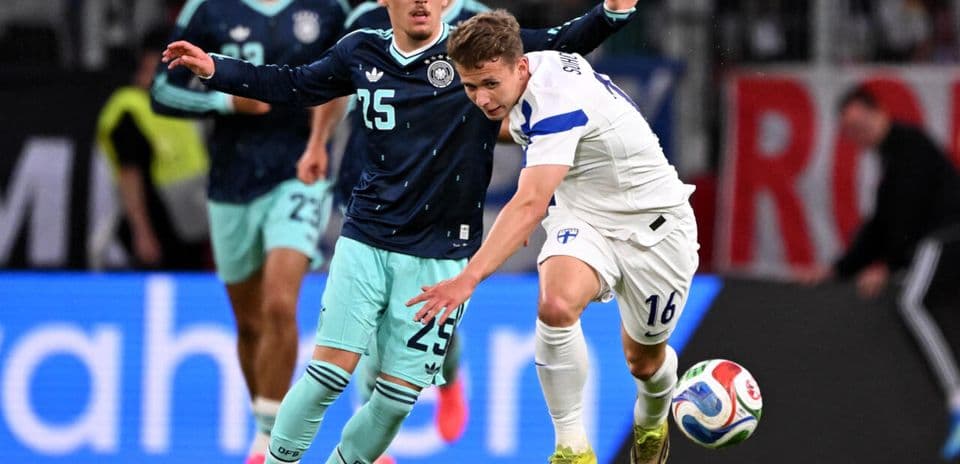 Jugador de Finlandia driblando mientras es marcado por alemán