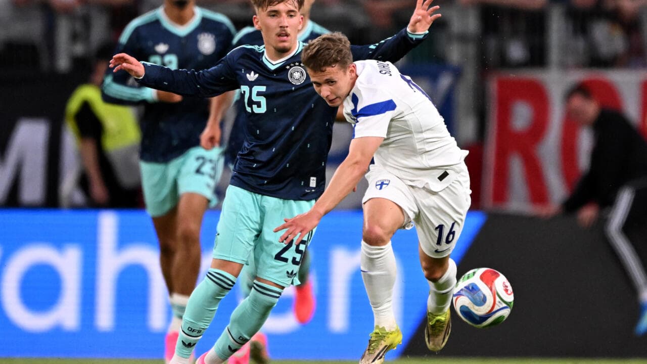 Jugador de Finlandia driblando mientras es marcado por alemán