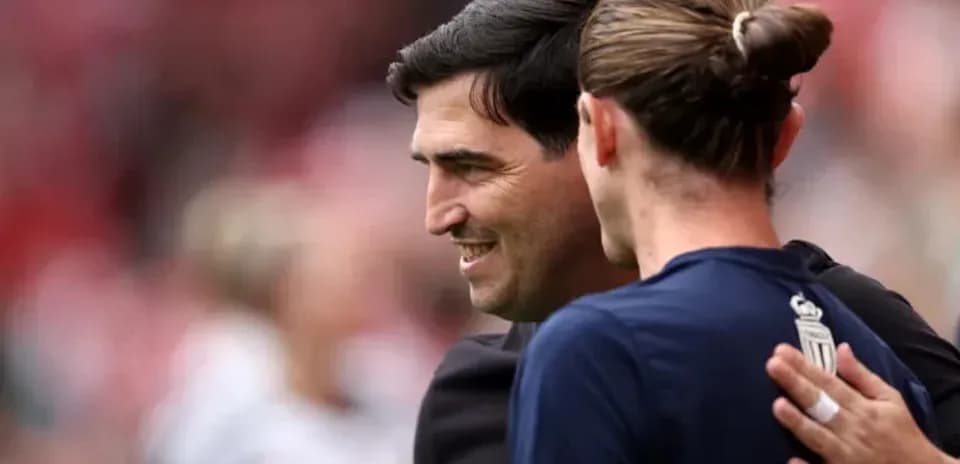Entrenador y jugador intercambiando saludos en el campo