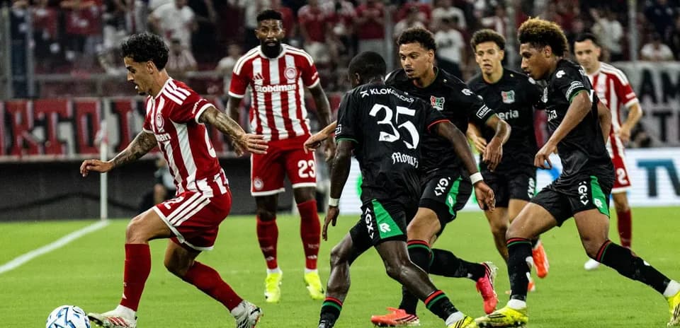 Jugador de Olympiakos driblando a defensores de NEC