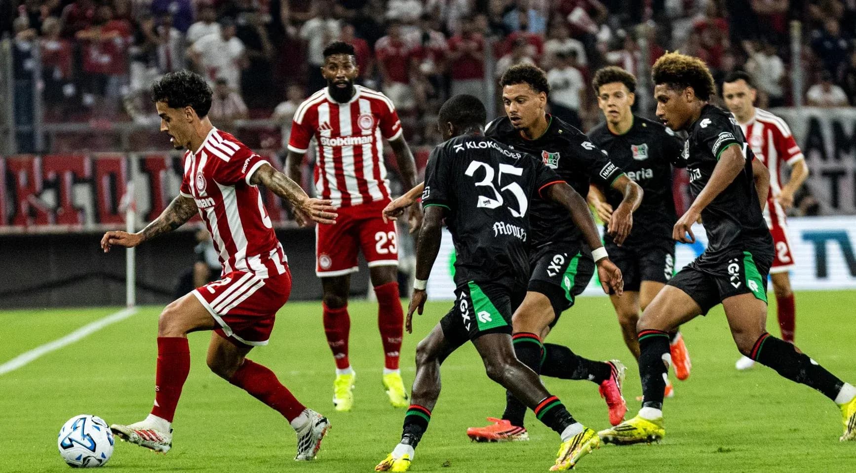 Jugador de Olympiakos driblando a defensores de NEC