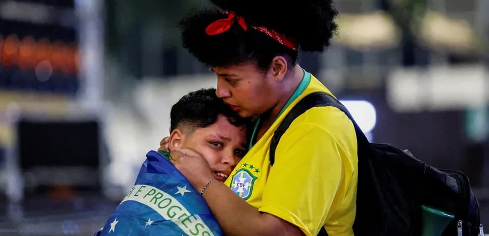 Mujer abrazando a niño envuelto en bandera brasileña