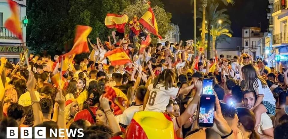Multitud celebrando con banderas españolas en la calle