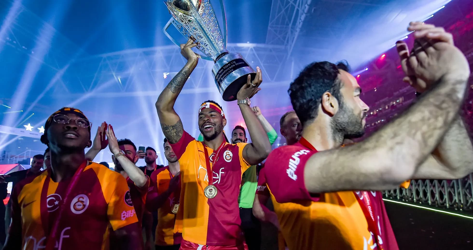 Jugador levantando trofeo con compañeros celebrando