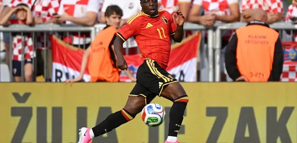 Jugador de Bélgica corriendo con balón en el campo