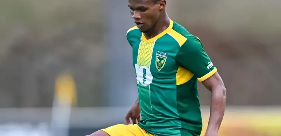 Jugador de fútbol con uniforme verde y amarillo en acción