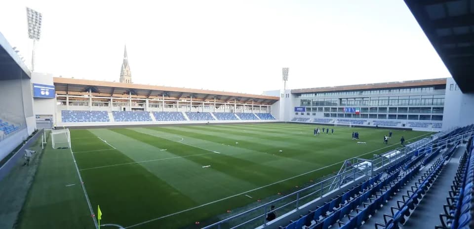 Campo de fútbol vacío con jugadores entrenando
