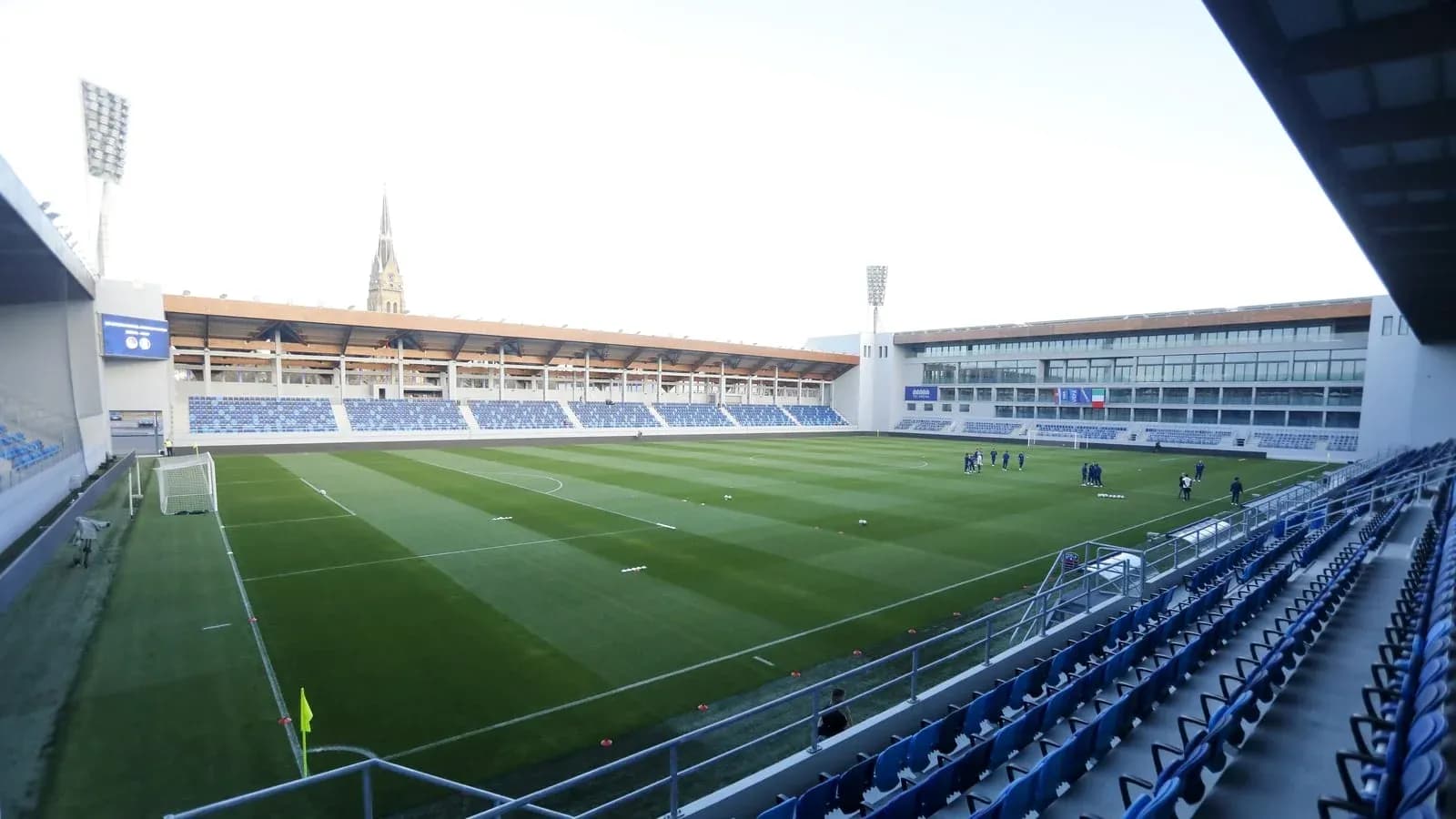 Campo de fútbol vacío con jugadores entrenando