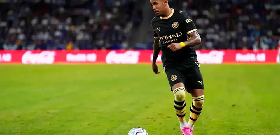 Jugador de fútbol corriendo con balón en el campo