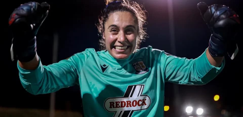 Portera celebrando con guantes en campo iluminado