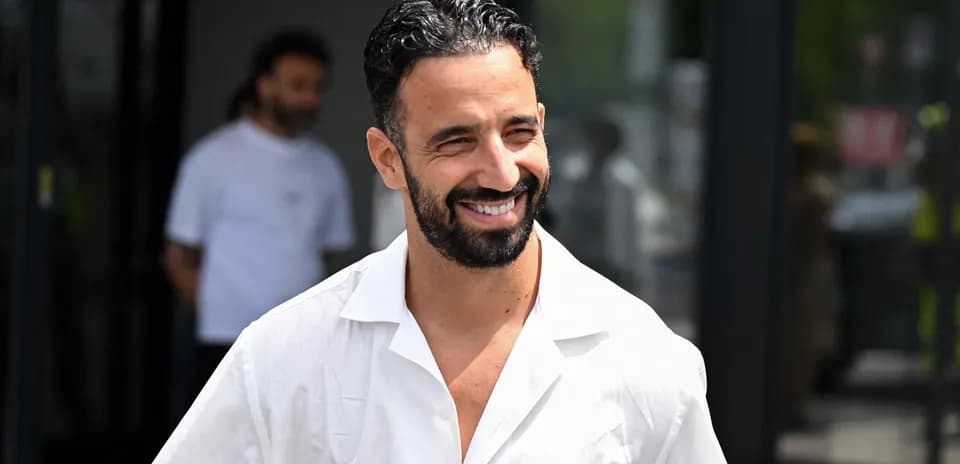 Hombre sonriendo con camisa blanca al aire libre