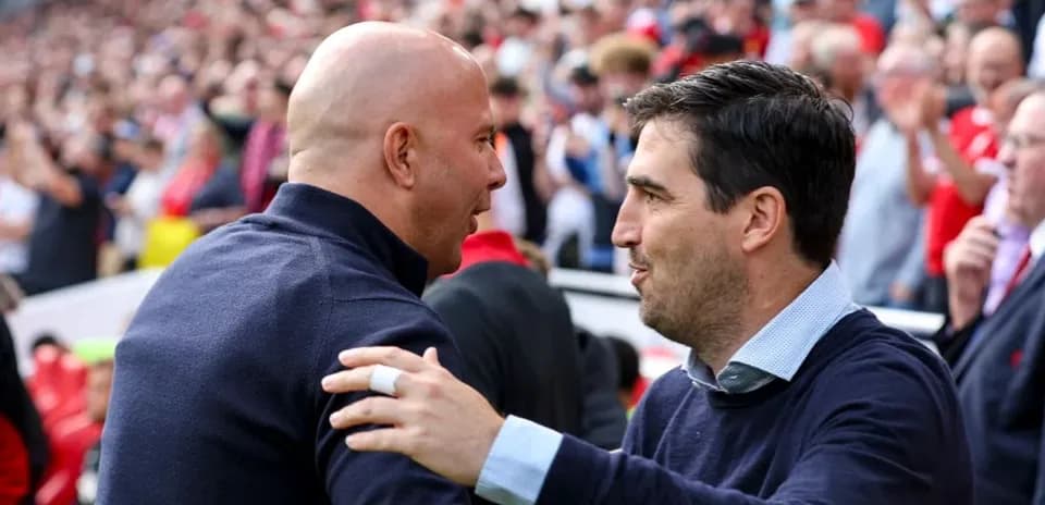 Entrenadores saludándose en un estadio lleno