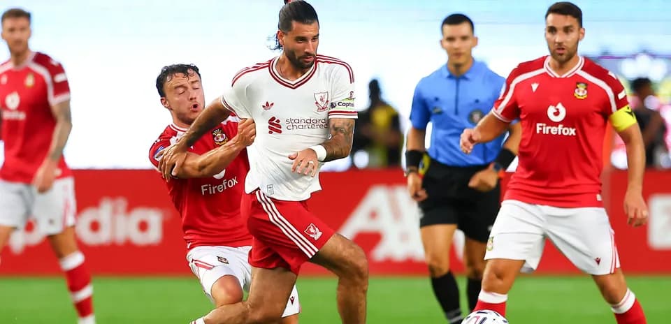 Jugador de Liverpool driblando mientras es marcado por rival
