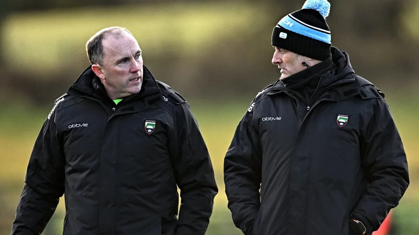 Entrenadores conversando en un campo de entrenamiento