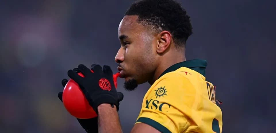 Jugador soplando un balón rojo en el campo