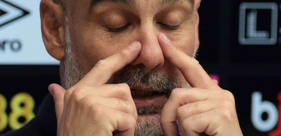 Entrenador tocándose la cara durante conferencia de prensa