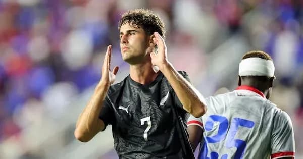 Jugador con camiseta negra levantando las manos en el campo