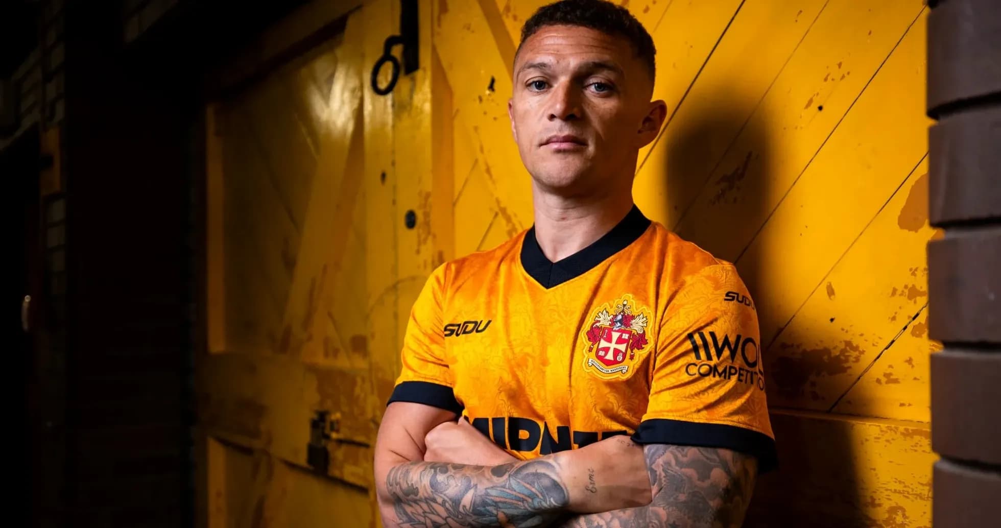 Jugador posando con camiseta naranja frente a fondo amarillo