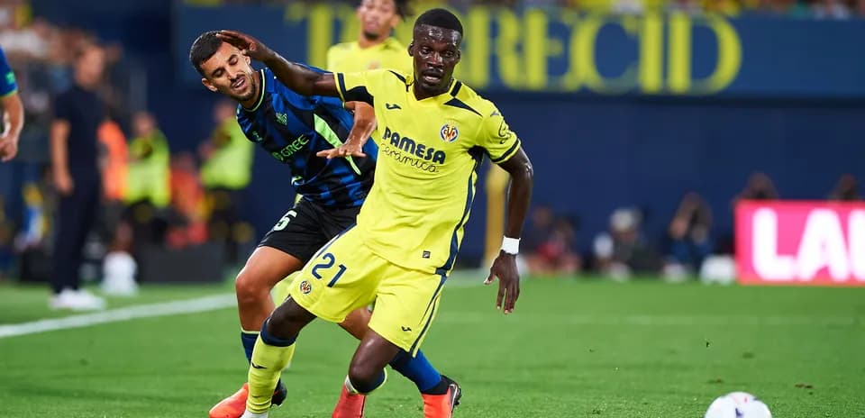 Jugador de Villarreal driblando bajo presión en el campo