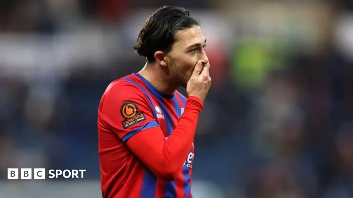 Jugador con camiseta roja tocándose la cara en el campo