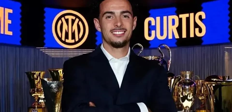 Persona sonriendo frente a trofeos en evento
