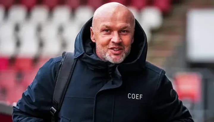 Hombre con chaqueta negra sonriendo en estadio