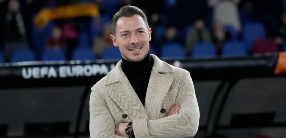 Hombre sonriendo con abrigo en estadio vacío