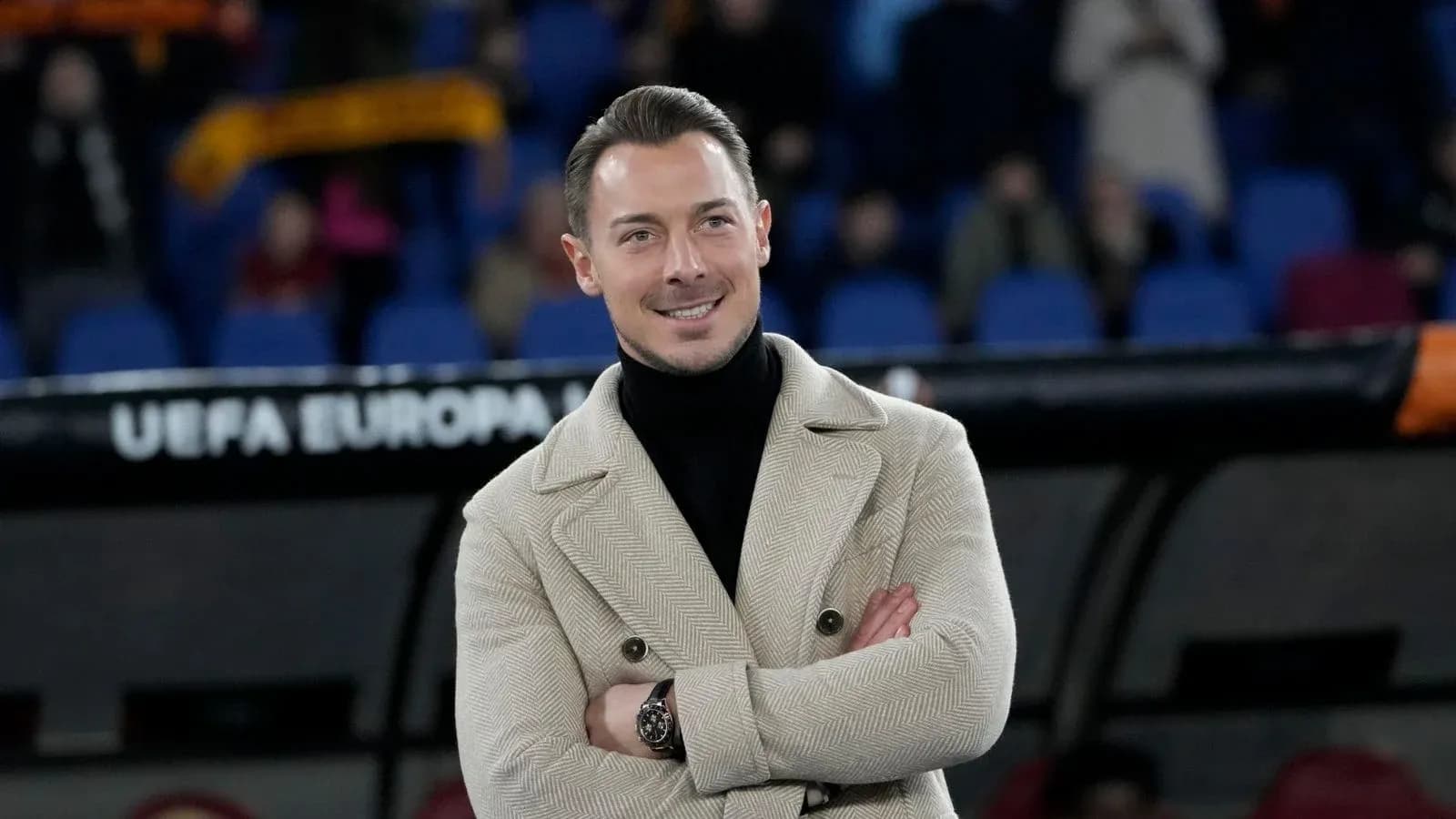 Hombre sonriendo con abrigo en estadio vacío