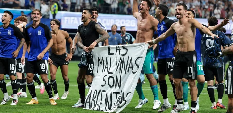Jugadores argentinos celebrando con una pancarta en el campo
