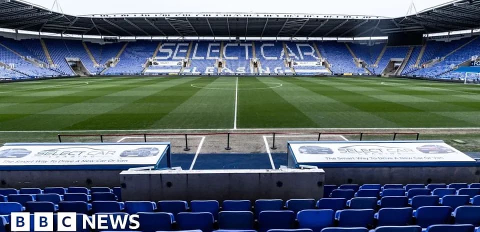Estadio vacío con gradas azules y césped verde