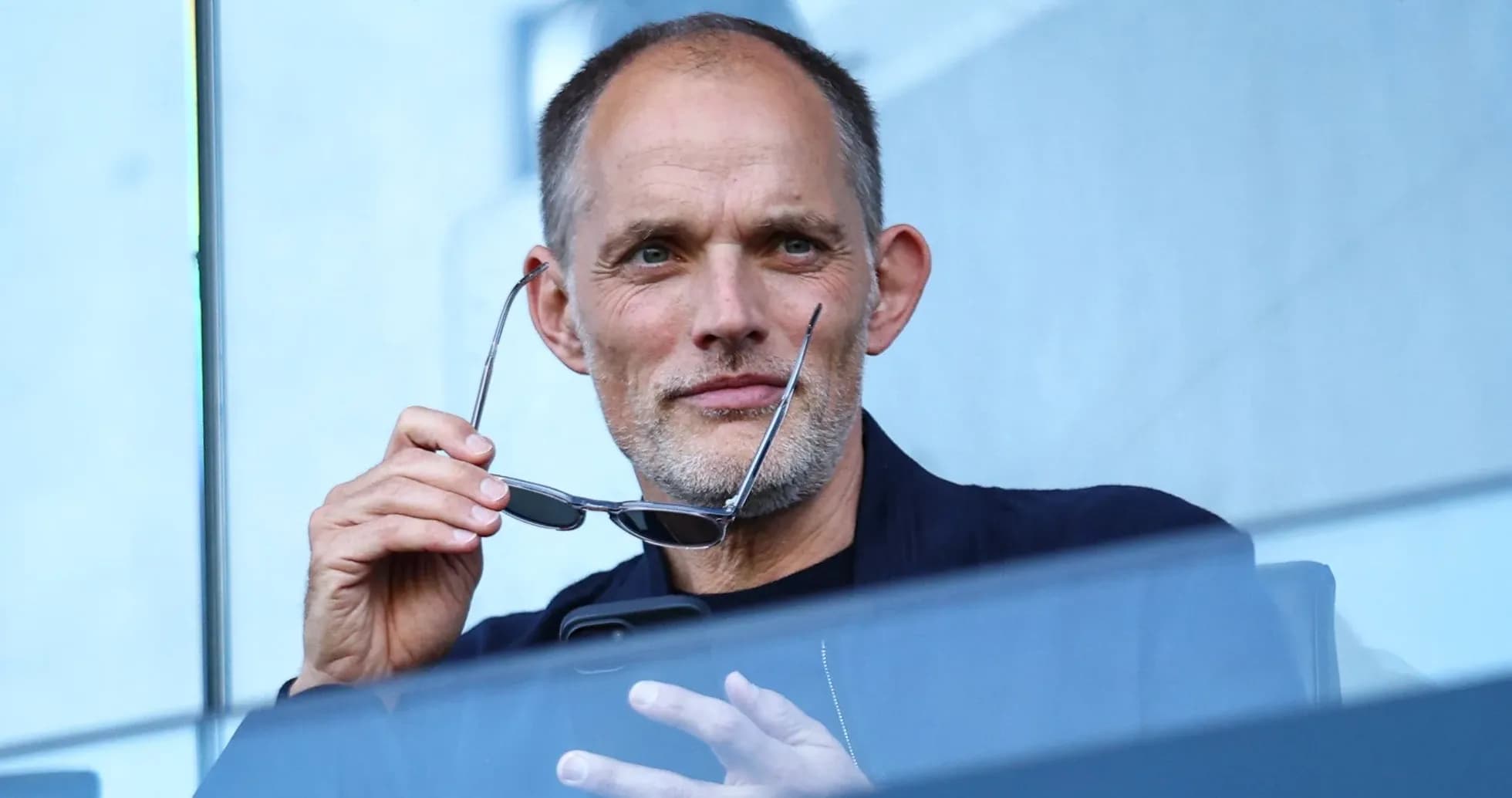 Hombre sosteniendo gafas en un palco deportivo