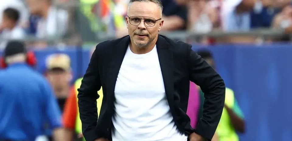 Entrenador caminando en el área técnica del partido
