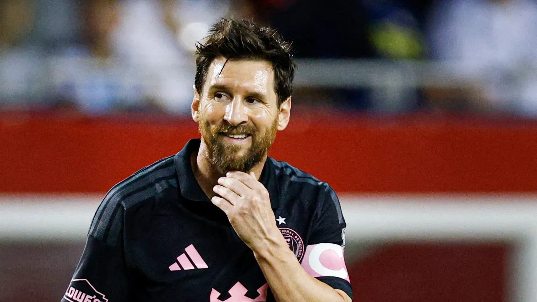 Jugador de fútbol con camiseta negra sonriendo durante el partido