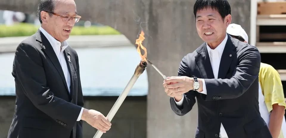 Dos personas encendiendo una antorcha durante ceremonia