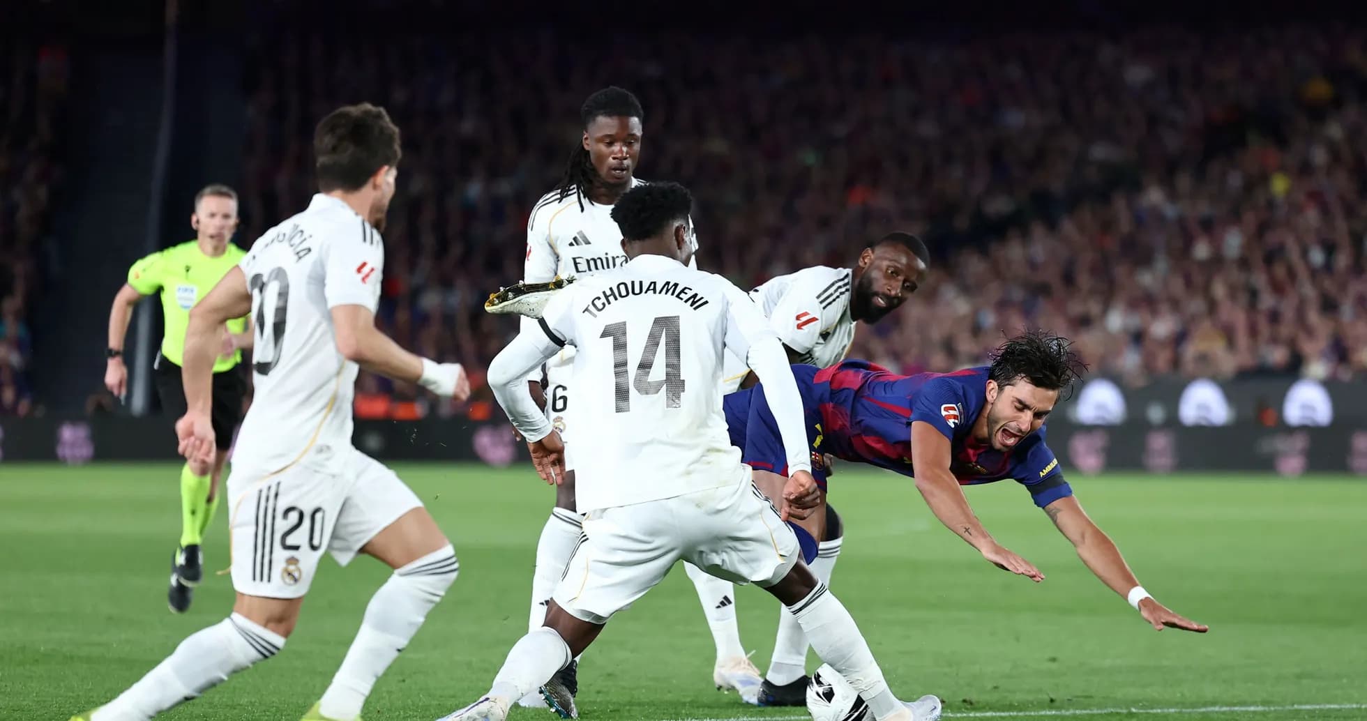 Jugador de Barcelona cayendo ante defensores del Real Madrid