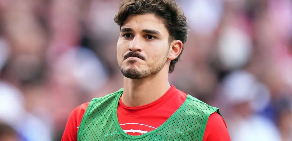 Jugador en la banca con pechera verde durante partido