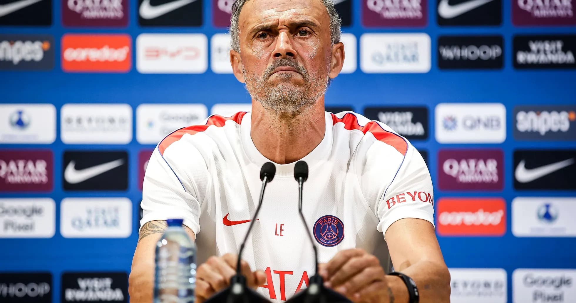 Entrenador en conferencia de prensa con logos de patrocinadores