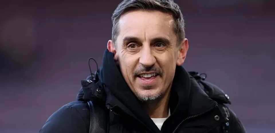Hombre sonriendo con abrigo negro en estadio