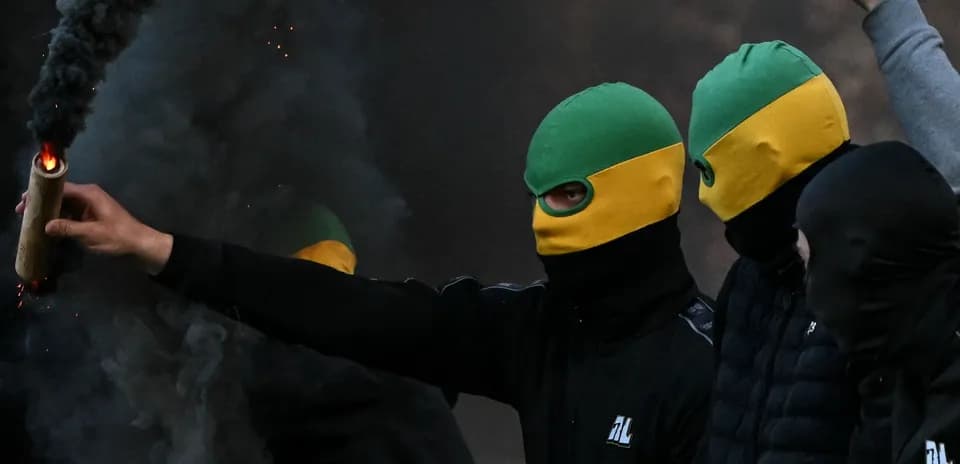 Person lanzando un objeto humeante en manifestación
