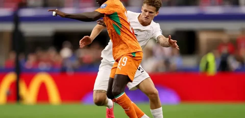 Jugador con camiseta naranja driblando a oponente en blanco