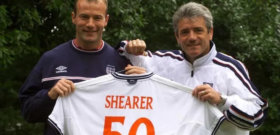 Jugador y entrenador sosteniendo camiseta con nombre Shearer