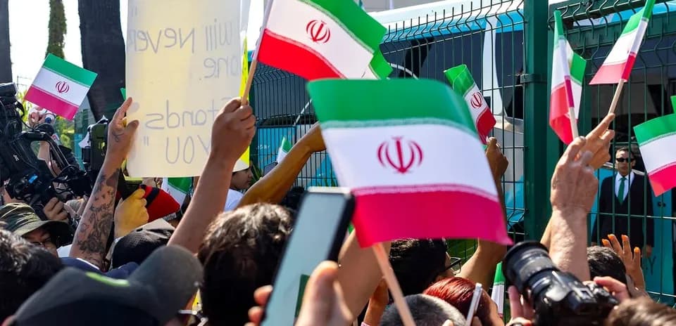 Multitud sosteniendo banderas de Irán durante una protesta