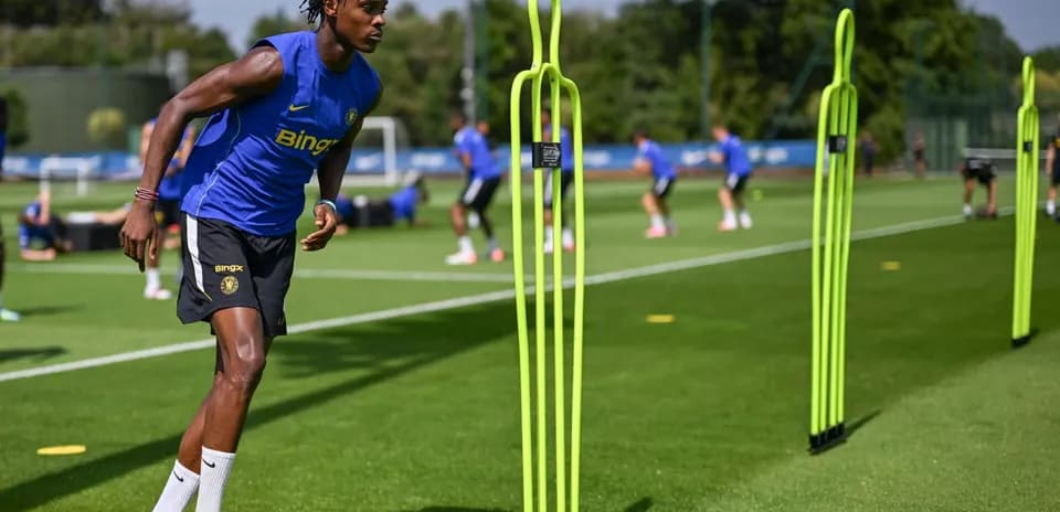 Jugador entrenando con conos en campo de fútbol