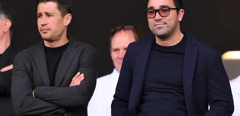 Dos hombres sentados en un palco de estadio