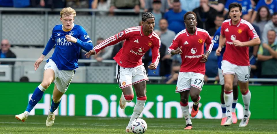 Jugadores de Manchester United corriendo tras balón en partido