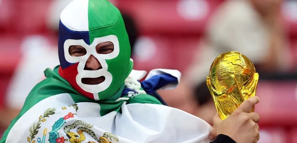A fan in a mask holding a World Cup trophy