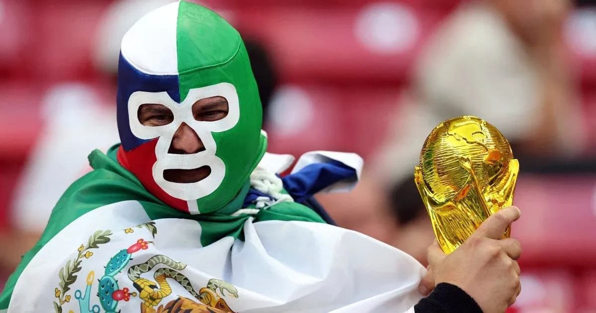 A fan in a mask holding a World Cup trophy