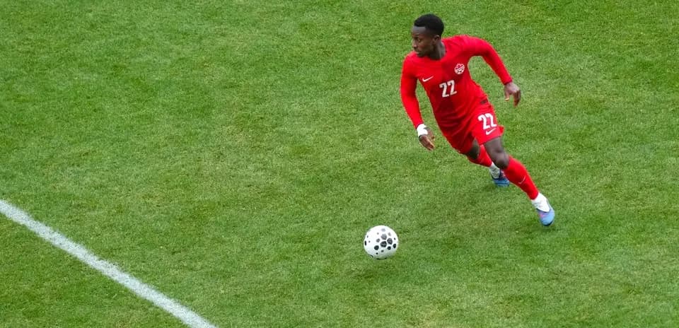 Jugador corriendo con balón en partido de fútbol